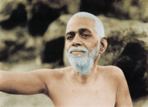 Photo of Ramana Maharshi with right arm out on the hill in color